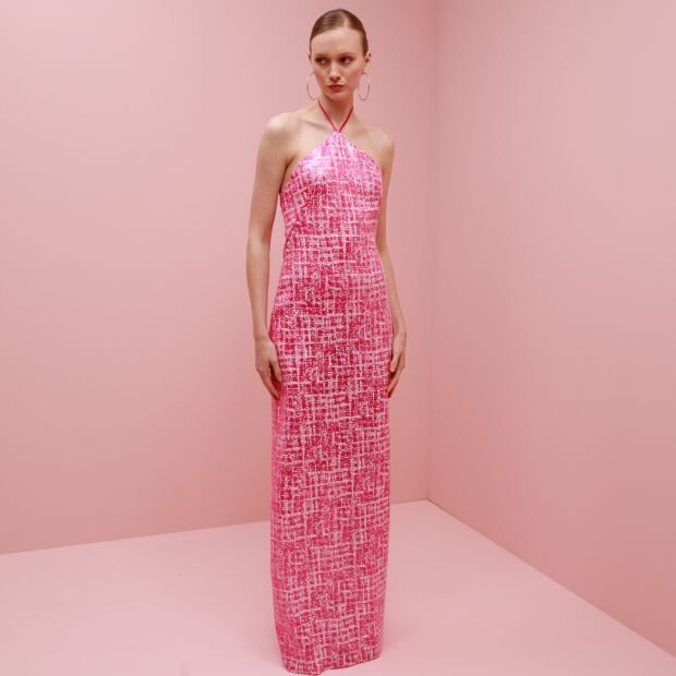 A model wearing a pink sequin halter maxi dress with slim, figure-hugging shape.