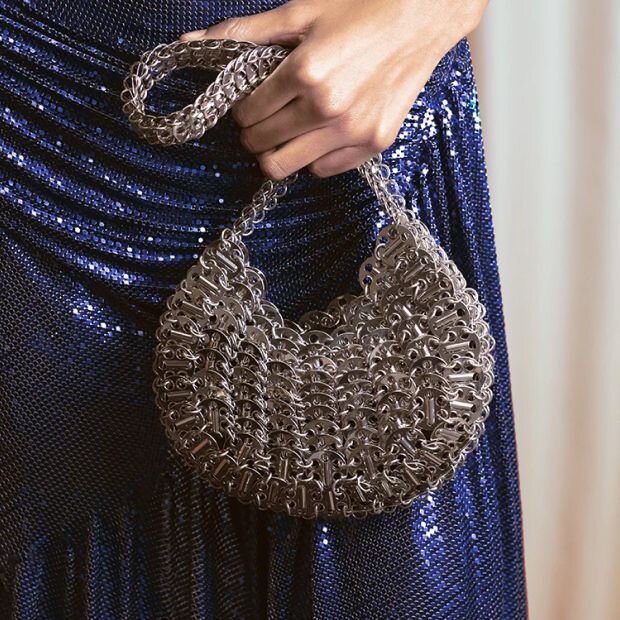 A closeup of a model carrying a silver metallic moon shaped bag.