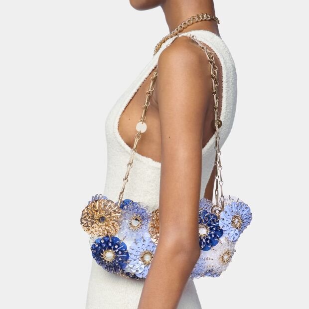 A model wearing a floral acrylic and gold chainmail shoulder bag.