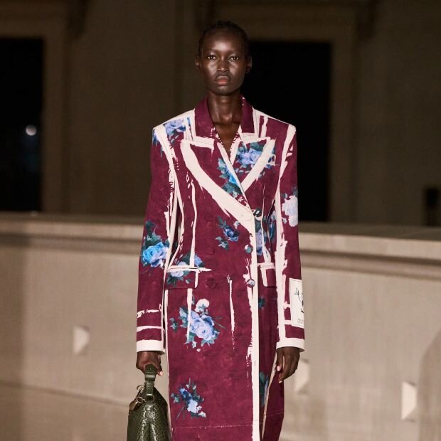 A model a plum, blue and white floral tailored coat.
