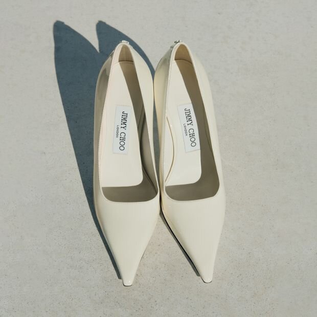 A pair of white leather pointed-toe pumps.