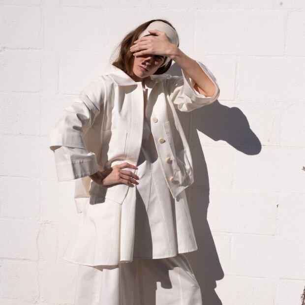 A model wearing a matching white cotton jacket and pants.