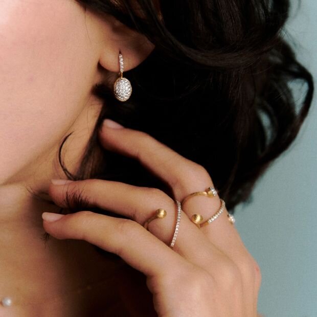 A model wearing 2 gold and diamond criss cross rings. 