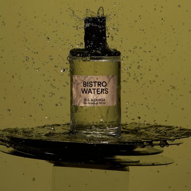 A transparent glass bottle of perfume with a black cap.