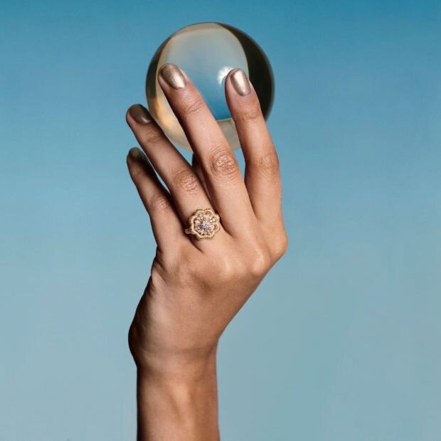 A model wearing a small lace flower 18K gold lab-grown diamond filigree band ring.