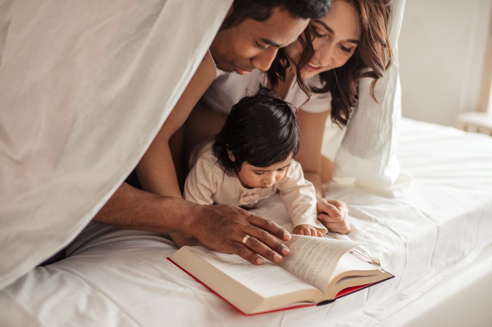 parents reading book with baby