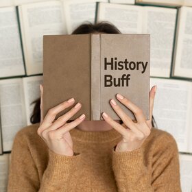 Women Holding Book in front of face entitled History Buff