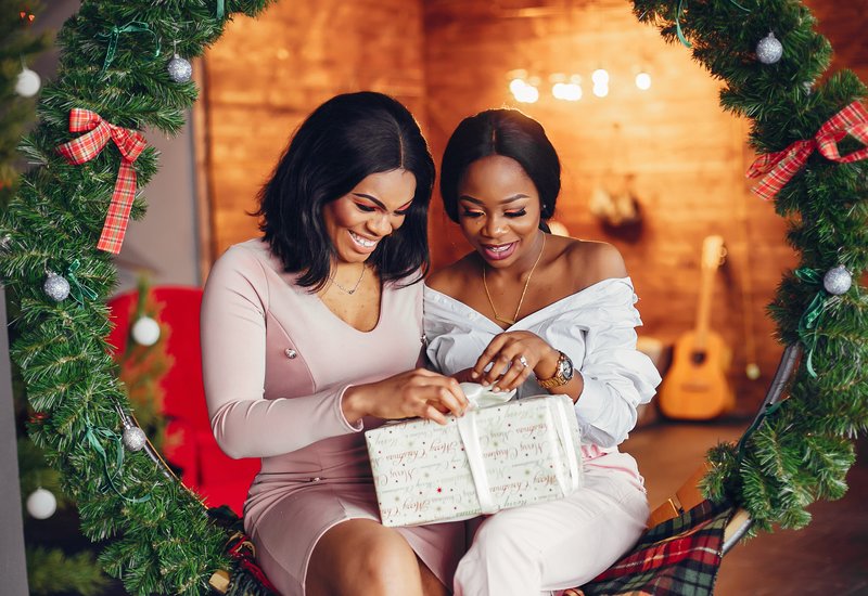 man and women smiling while holding wrapped gifts