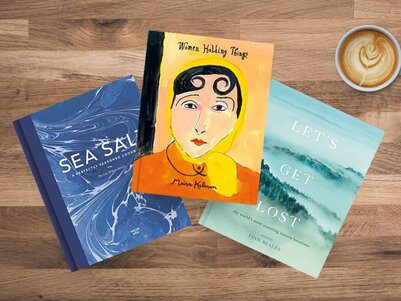3 Coffee Table Books laying on table. Women Holding Things by Maria Kalman. Let's Get Lost: The World's Most Stunning Remote Locations Finn Beales. Sea Salt: A Perfectly Seasoned Cookbook by Lea-Wilson Family, Anna Shepherd, Liz Haarala (Pht) Hamilton, 