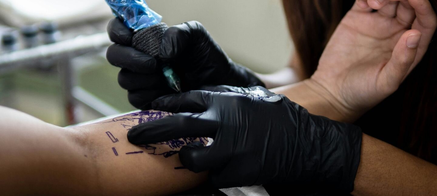 Tattoo Artist tattooing an arm 