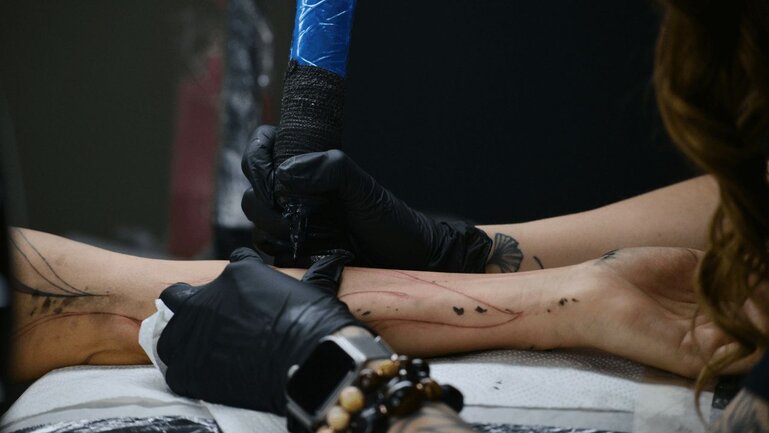 Tattoo artist doing a tattoo on an arm