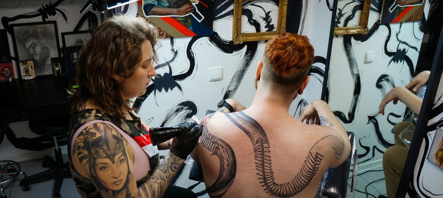Female tattoo artist making a back tattoo