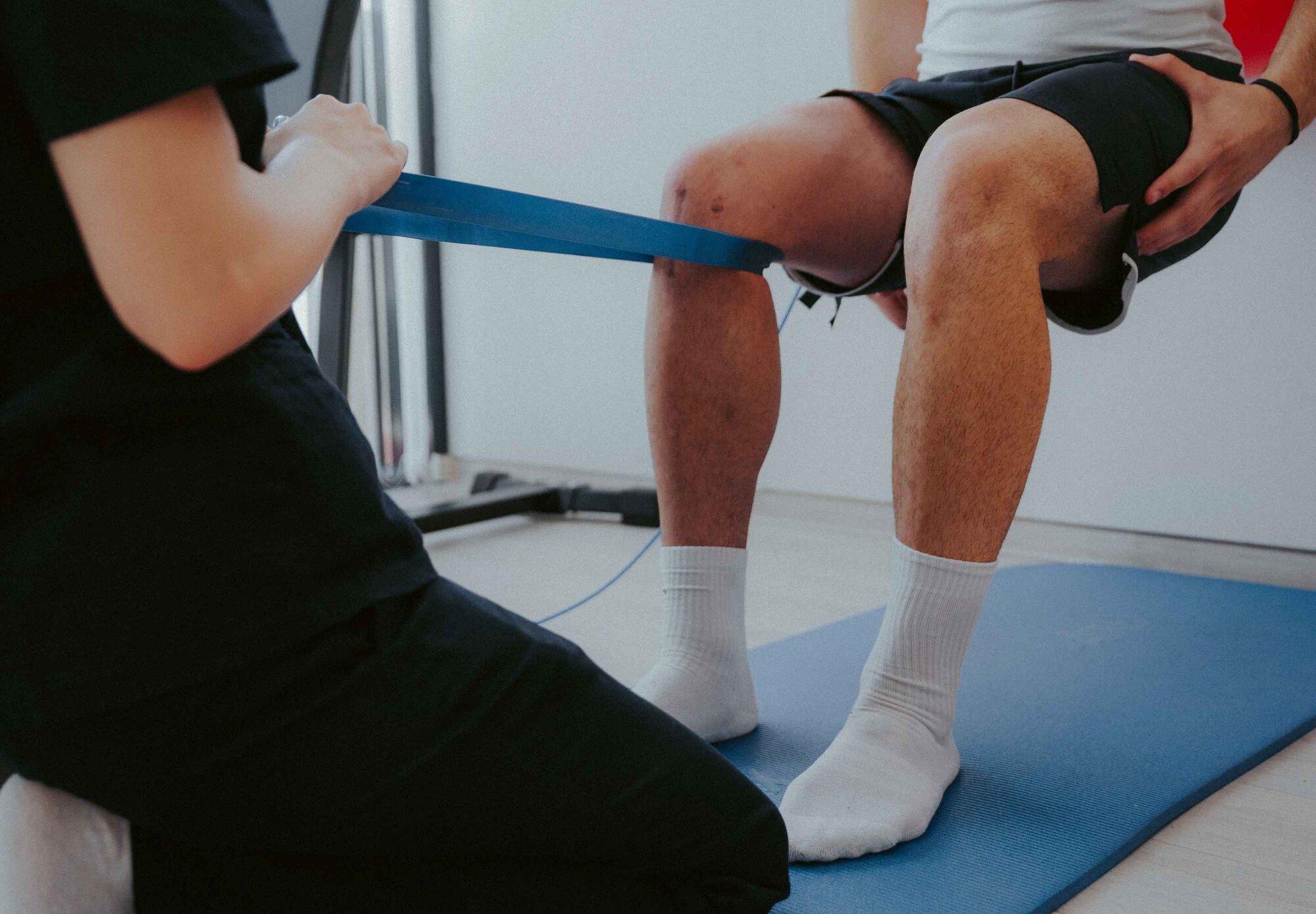 Mann macht Kniebeuge bei Sportphysiotherapeuten