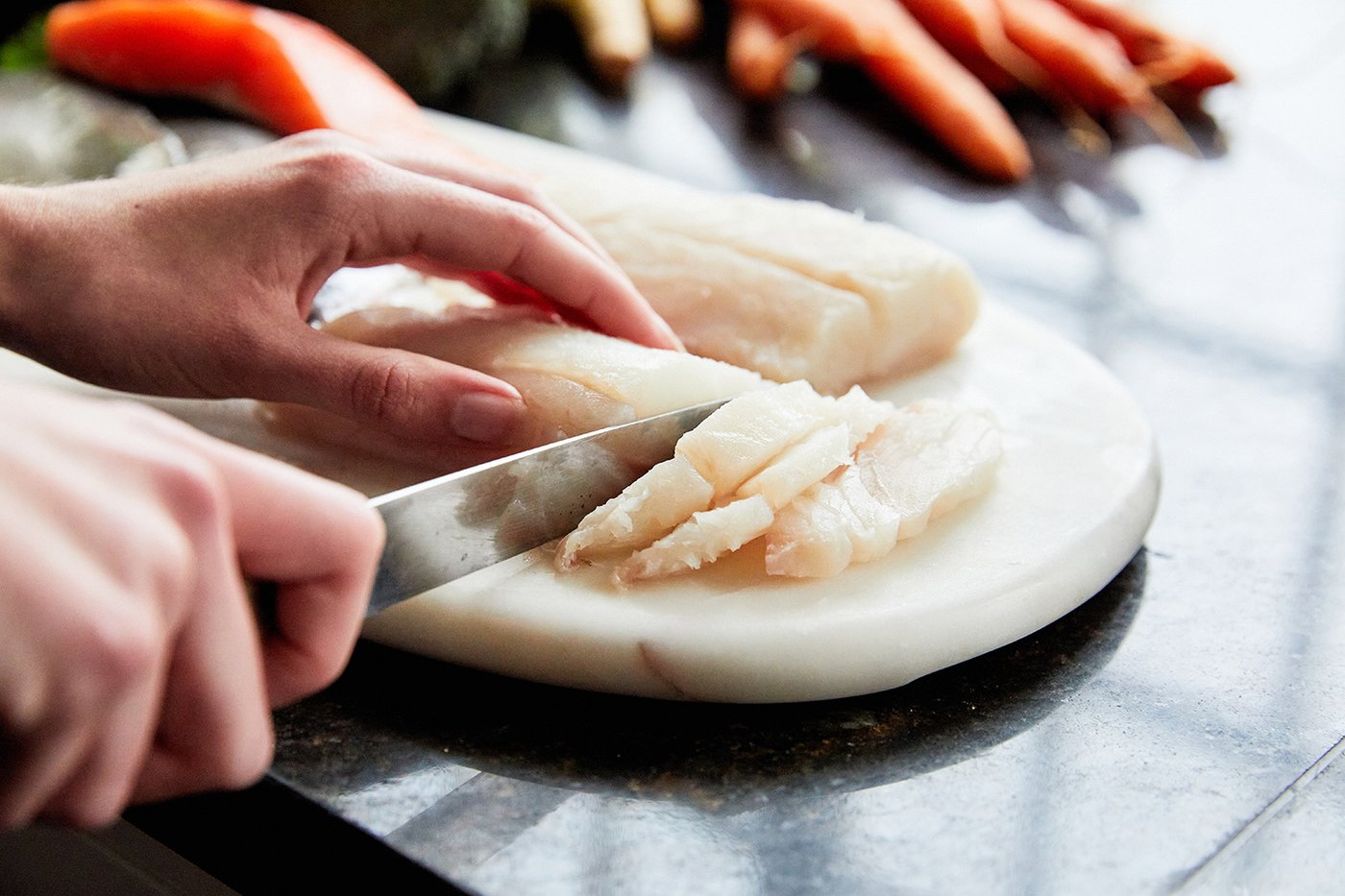 Someone cutting raw meat on a chopping board