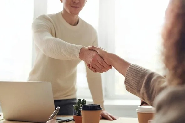 An attorney and a client shaking hands across a table.