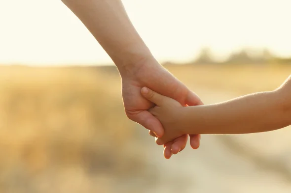 A child and his parent holding hands