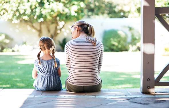 A mother and her child sitting on a porch