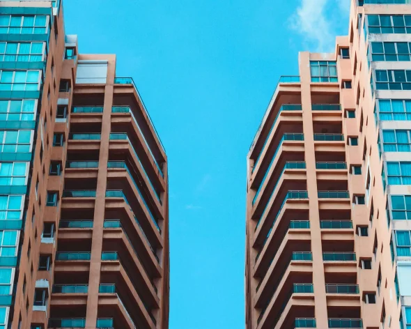 Modern high-rise buildings with balconies against blue sky.