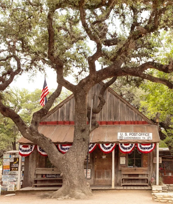 Rustic Luckenbach post office with oak tree and flag decor.