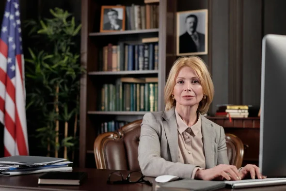 Experienced attorney in a professional office setting, seated at a desk with legal books and an American flag in the background, symbolizing legal expertise and authority.