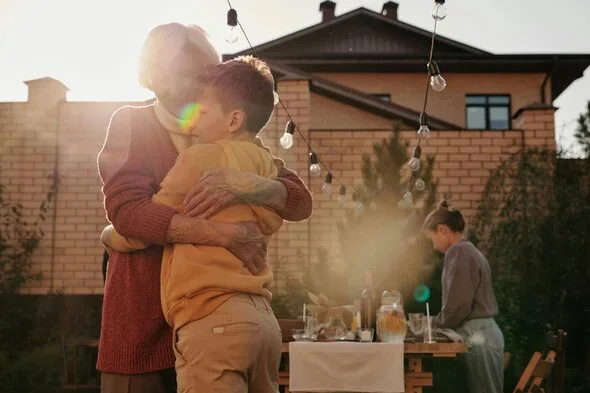 Grandmother hugging her grandson warmly outdoors near a dining table, symbolizing familial bonds and emotional support during life changes, such as child support modifications.