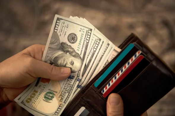 A person taking 100USD bills out of a wallet