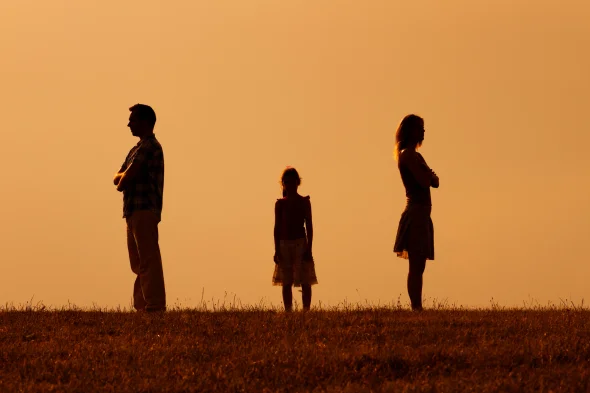 Two parents standing in opposite directions and their child in the middle.