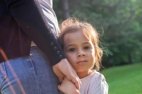 A child holding hands with her mother, resting her head on her lap.