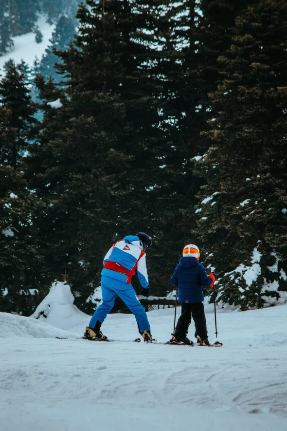 Parent and child skiing together on a snowy mountain, representing a winter activity and the bonding experience during outdoor adventures in a family setting.