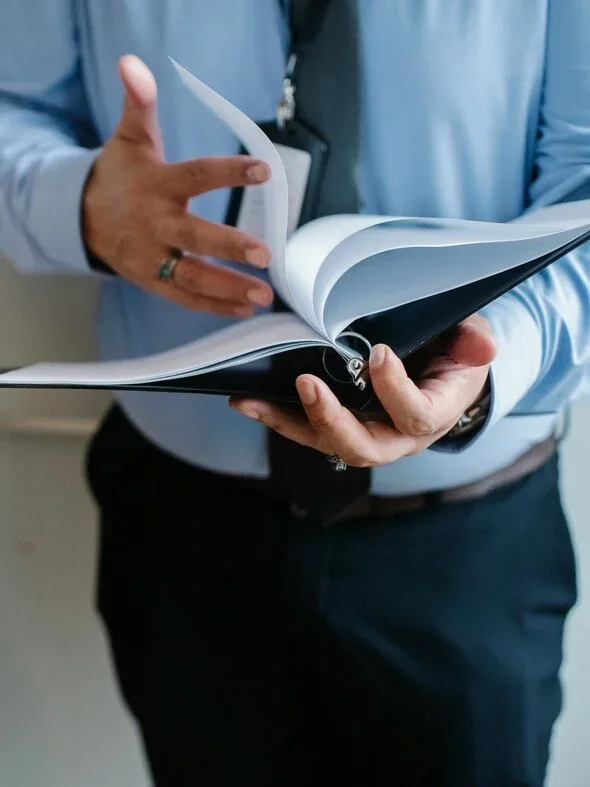 A lawyer flipping through a binder wearing a blue shirt and tie.