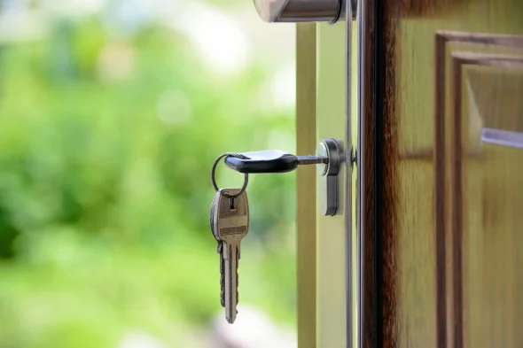 A key inserted into a door lock with a blurred green background.