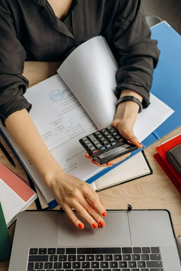 Close-up of a person holding a calculator and managing paperwork, symbolizing financial planning and considerations during a divorce process in Arizona.