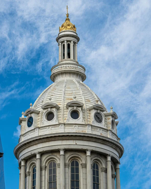 A white domed structure with gold accents against a blue sky.