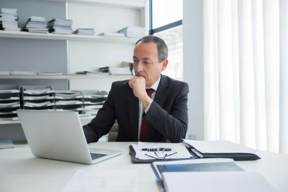 Attorney reviewing legal documents on a laptop in a formal office.