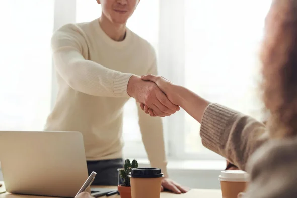 A man in a white shirt shaking hands with his attorney