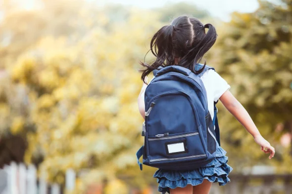 A child wearing a backpack walking in the street