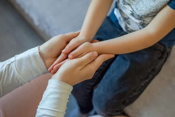 A child and his parent holding hands