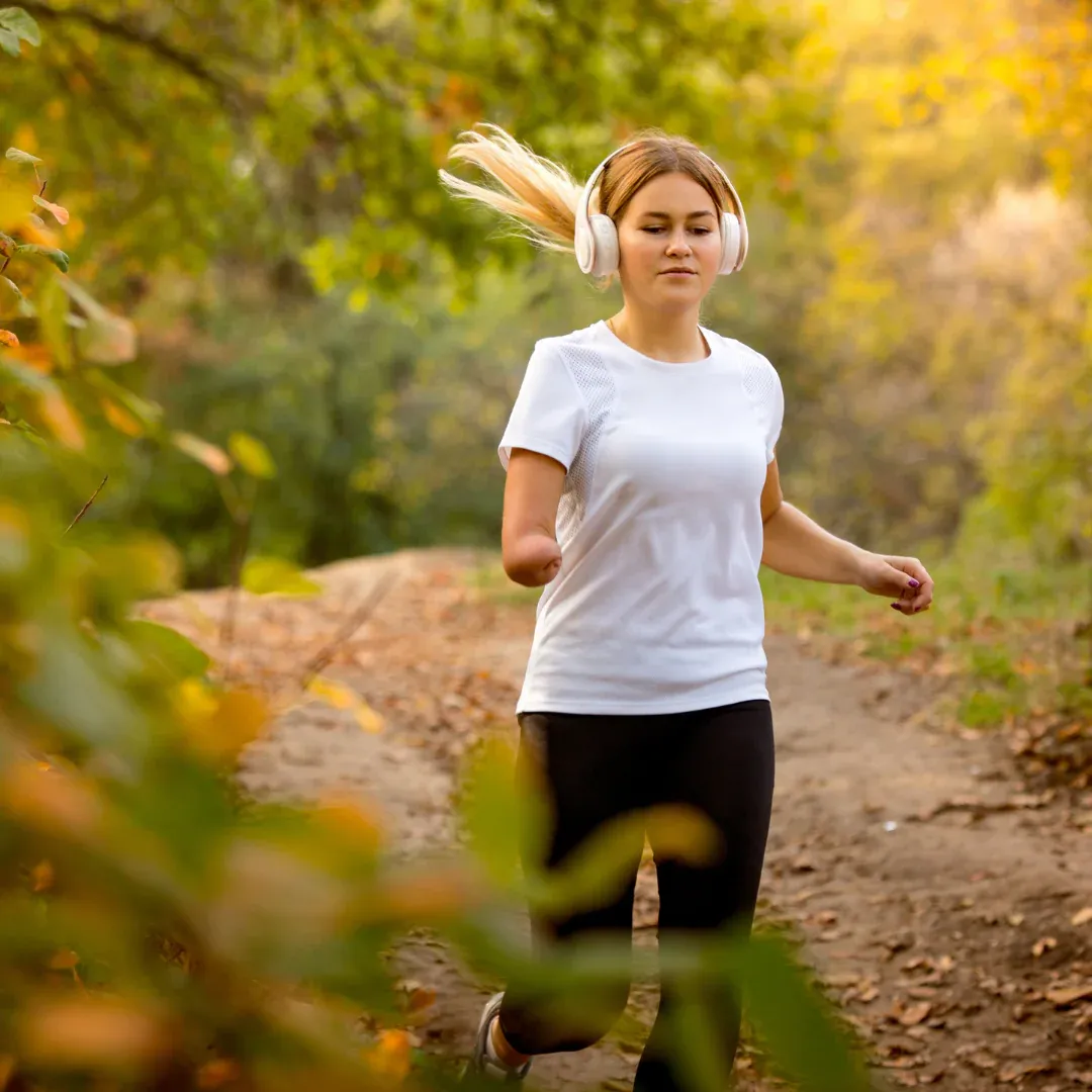 A woman is jogging in the woods.