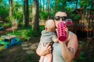 Woman drinking True Lemon drink while holding her baby.