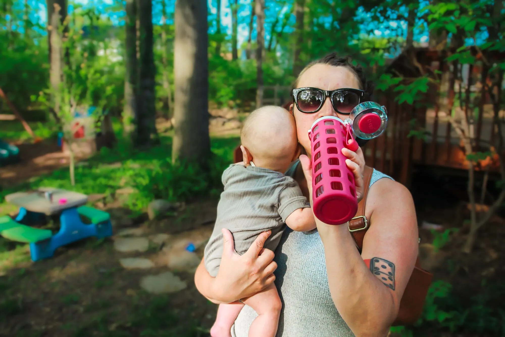 Woman drinking True Lemon drink while holding her baby.