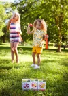 Two girls blowing bubbles outside. Three boxes of True Lemon Kids are in front of them.