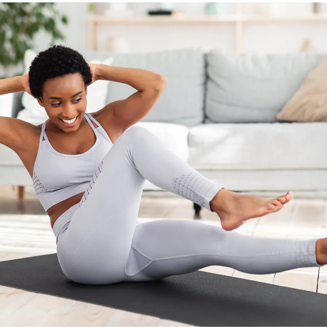 A woman is doing an exercise on a mat in her living room.