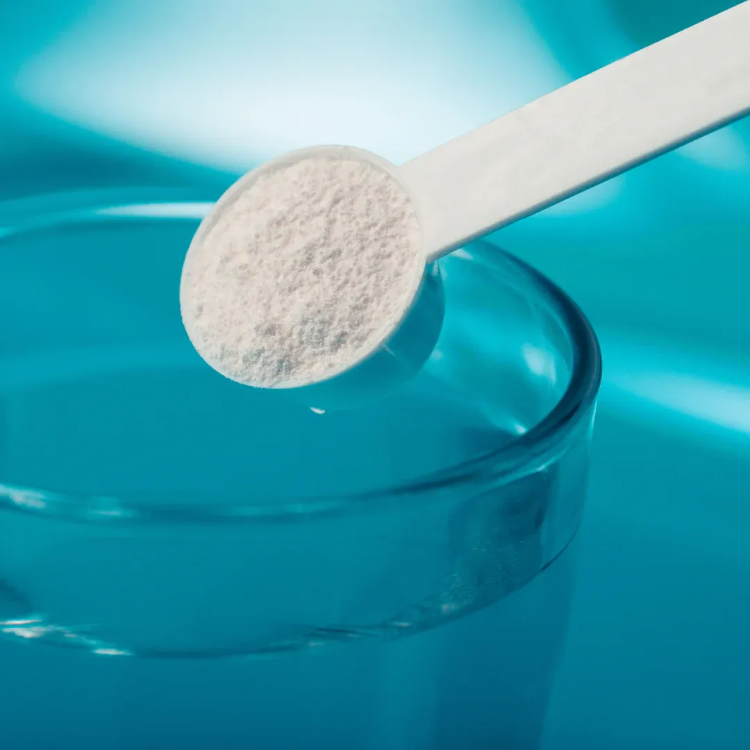 A scoop of electrolytes is being put into a glass of water.