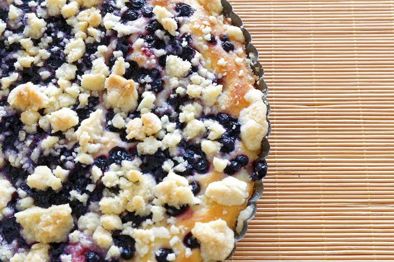 A slice of moist blueberry orange crumb cake with a golden crumble topping, ideal for breakfast or brunch.