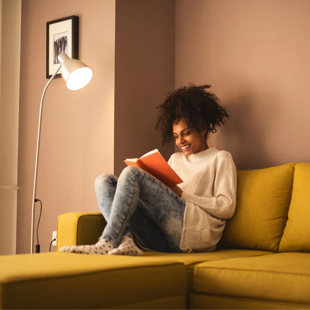 A woman on a couch reading a book.