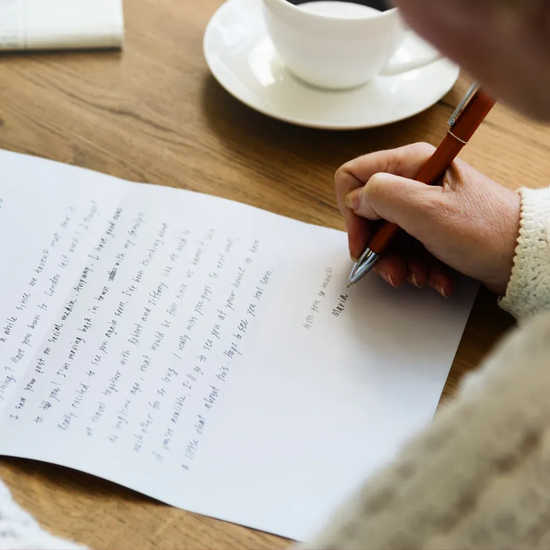 Someone writing a letter at a table.