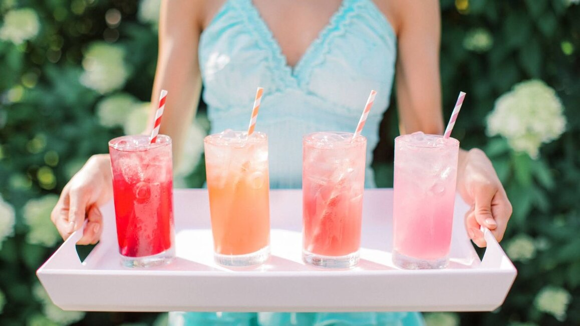 Woman Holding A Tray With Pink Lemonade And Other Varieties