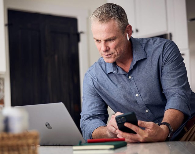 man working on smartphone and laptop