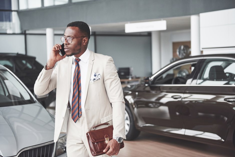 car sales employee talking on a cell phone in the car lot