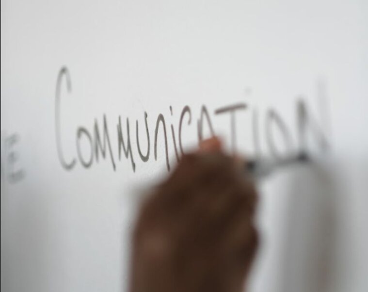 the word "communication" written on a dry-erase board